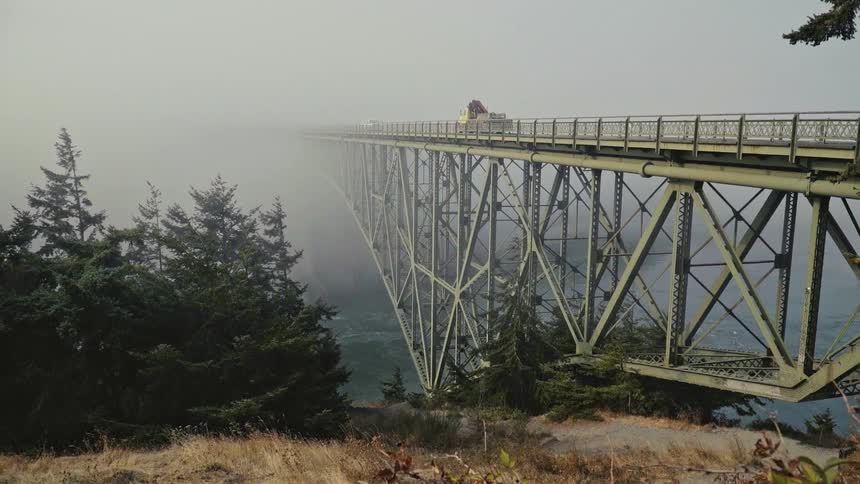 A truck is traveling over the foggy bridge