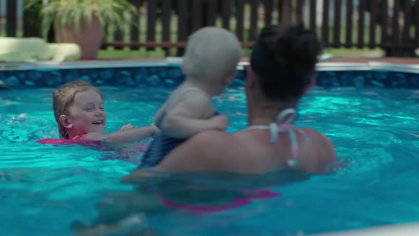 A woman is in the pool with her children smiling