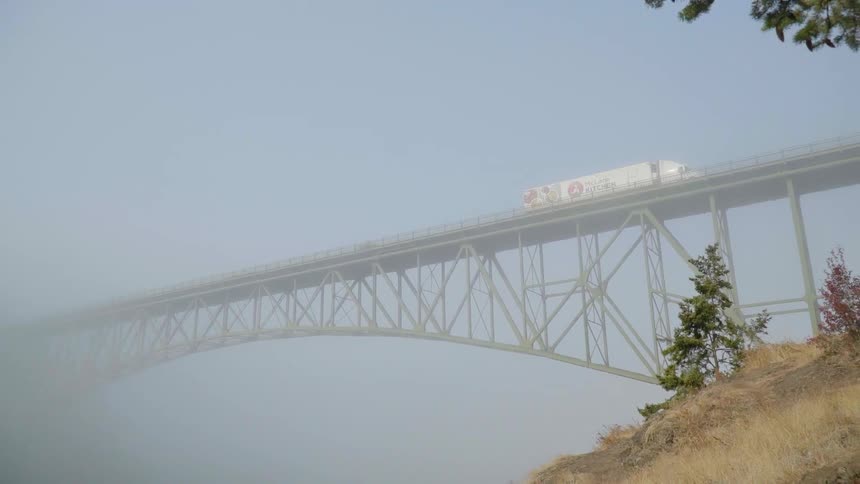 A big rig transport truck travels over a bridge