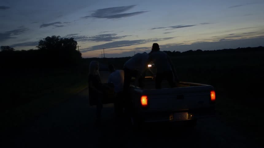 Two people hop in the bed of a pickup truck