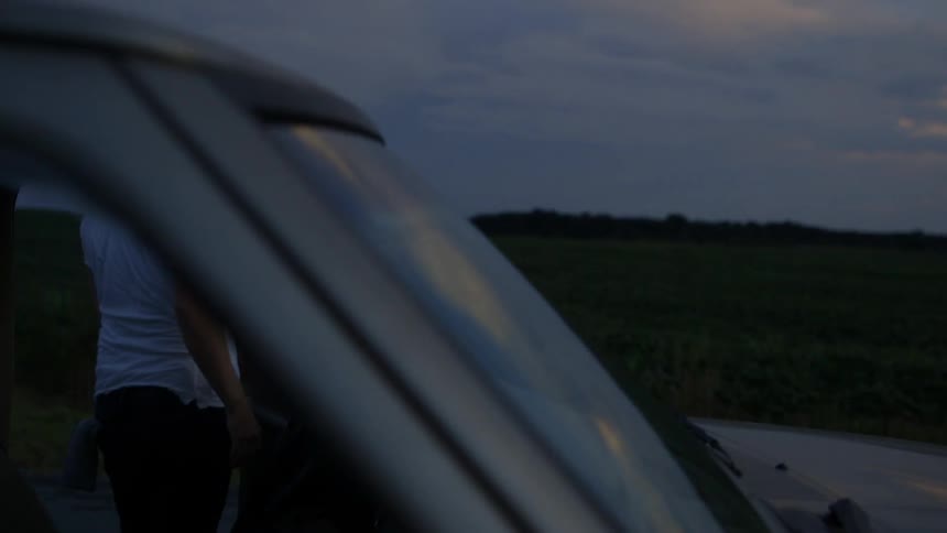Man exits truck in a rural field at dusk