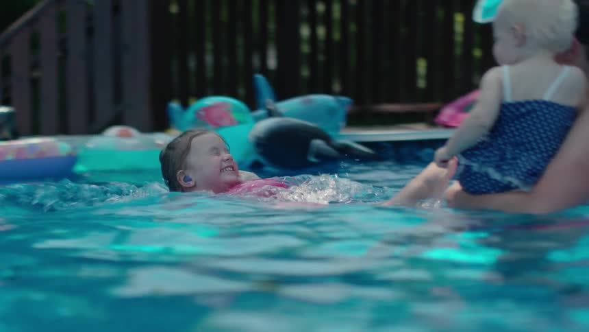 A woman is in the pool with her two kids playing