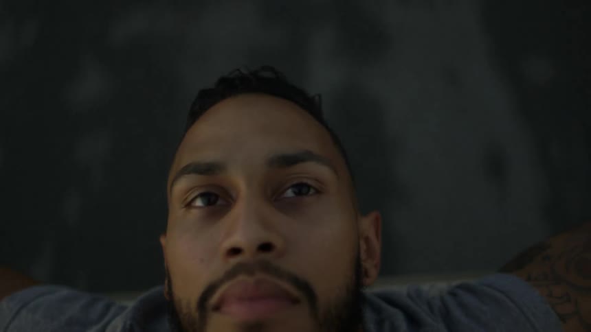 A man leans back in the bed of a moving truck
