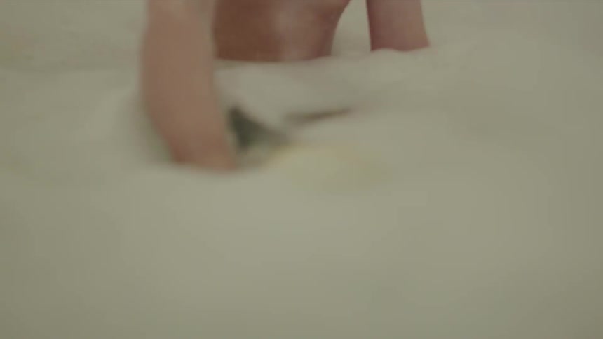 Child plays with a rubber duck in a bathtub