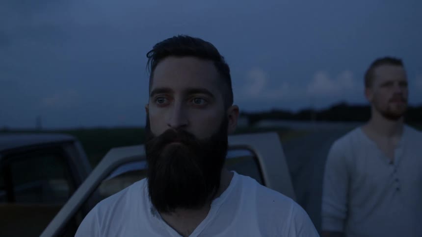 Two men standing outside of a vehicle at night