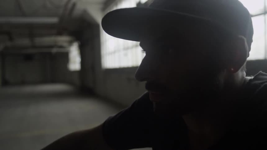 A man is sitting in a dark warehouse