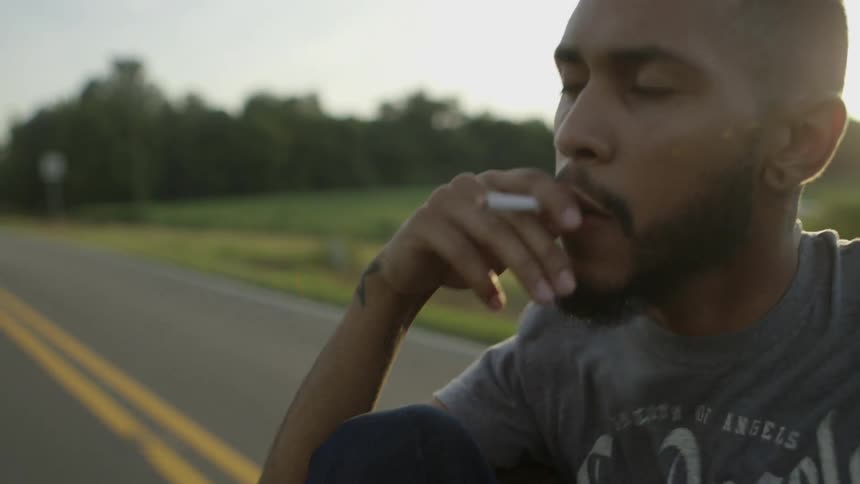 A man is smoking a cigarette in a moving vehicle