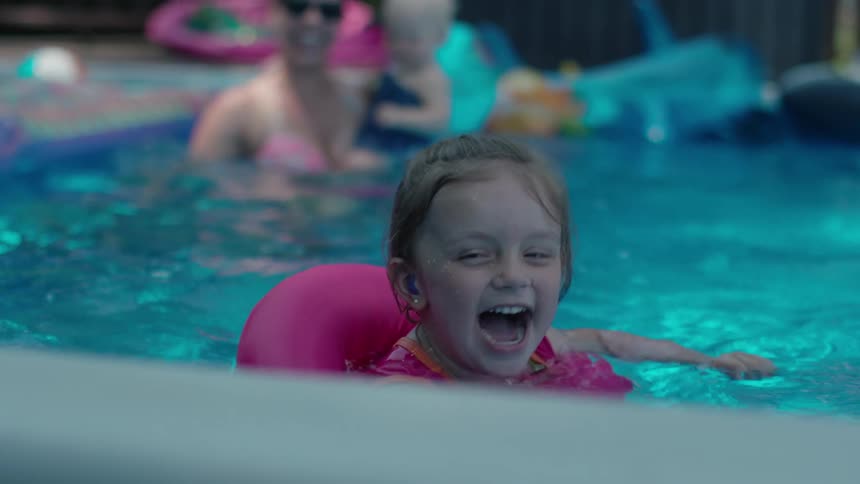 Woman and children play in swimming pool