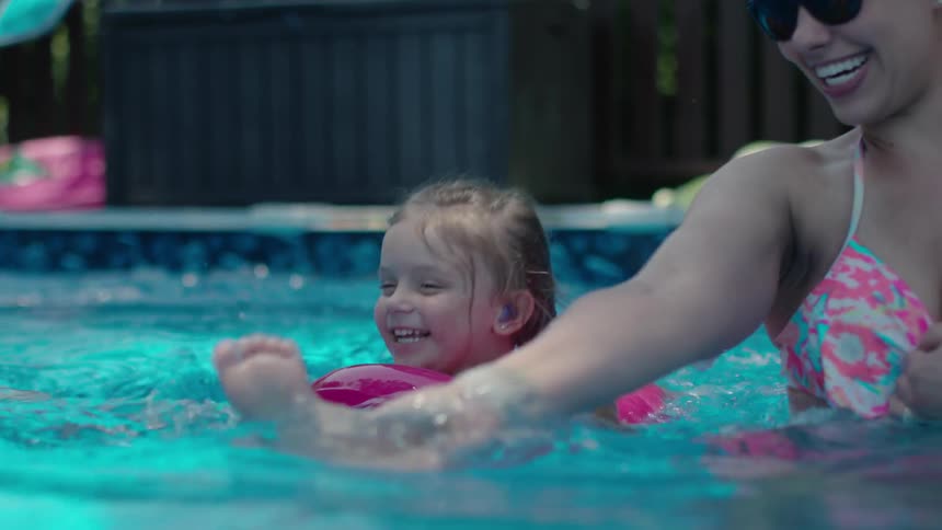 A woman and two kids are playing in the swimming pool
