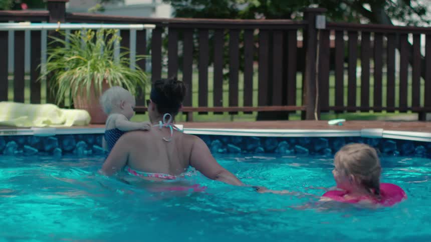 A mother plays with her children in a pool during the day