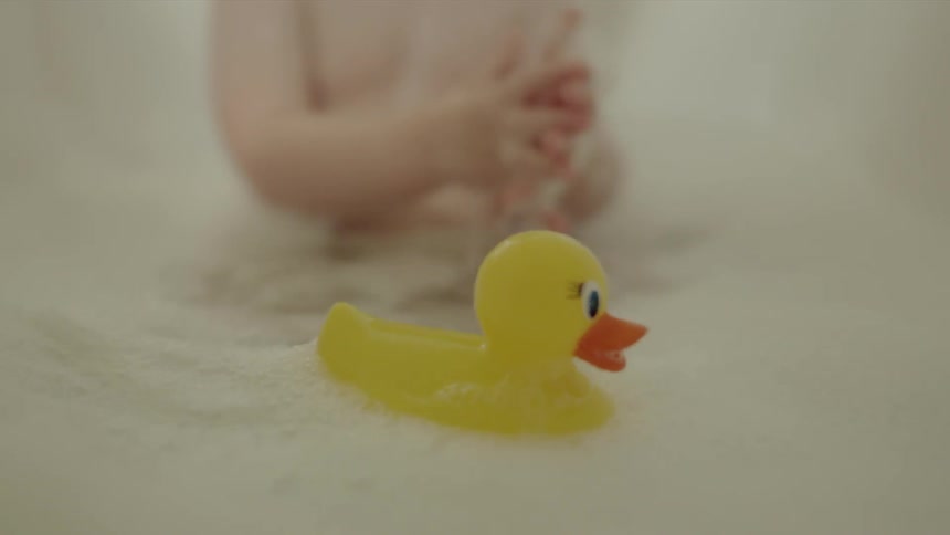 A baby is taking a bubble bath with a rubber ducky