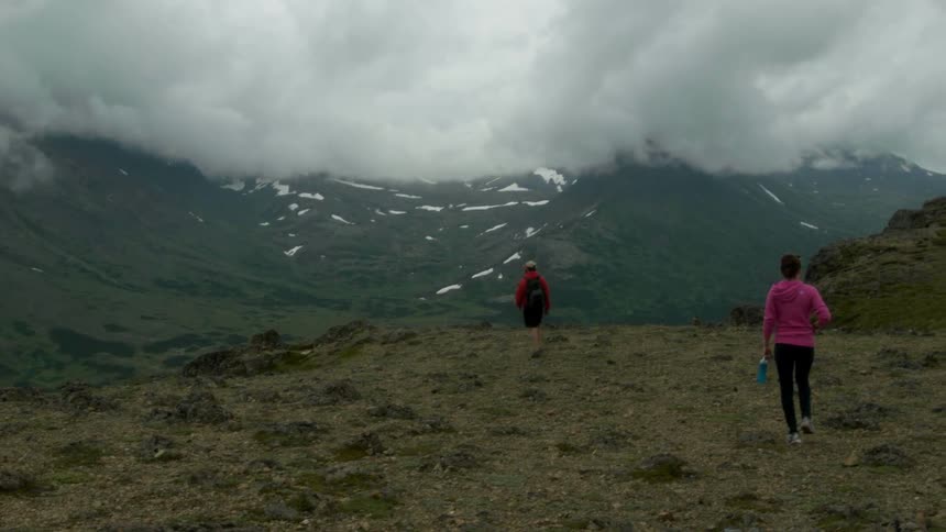 Man and woman hike outside by mountains on a cloudy day