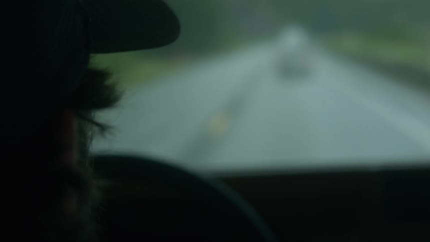 A man in a head drives down a rainy highway