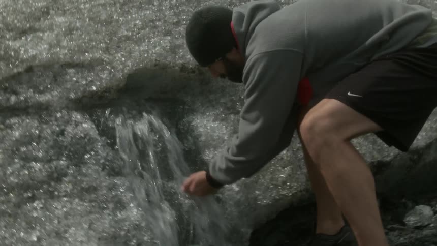 Man drinks from stream in snowy mountains