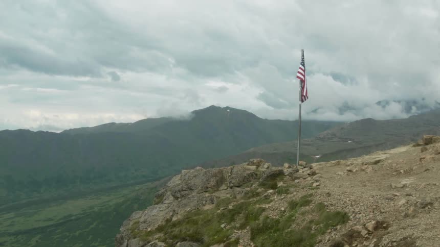 An american flag is mounted atop a mountain