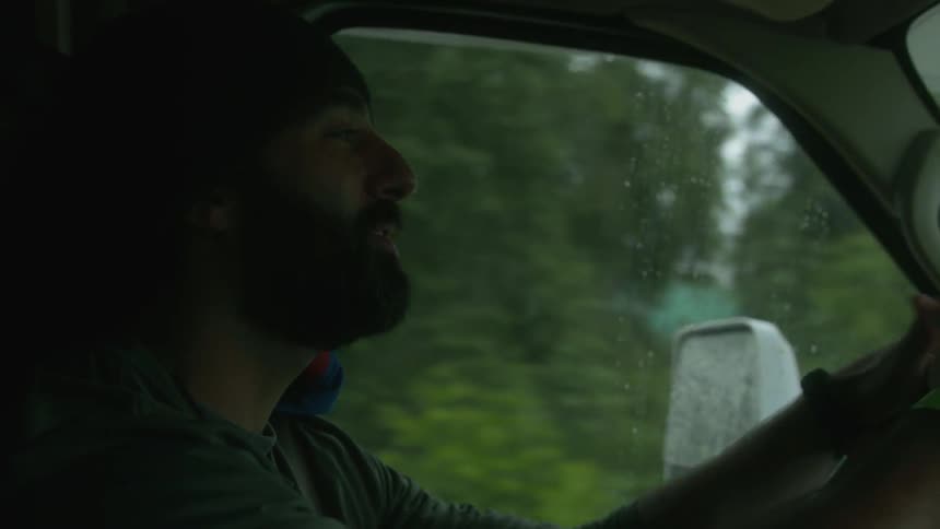 A man is singing and dancing to music as he drives in the car