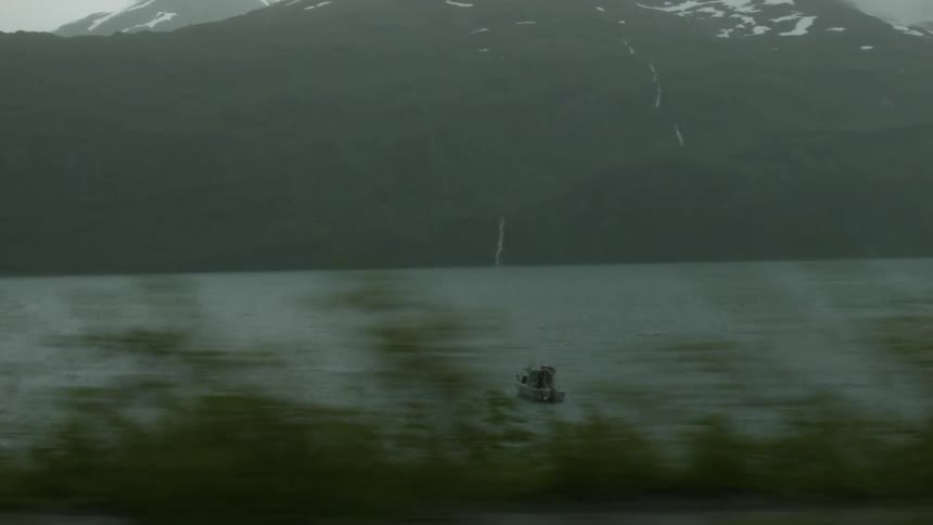 A boat travels in a lake near mountains