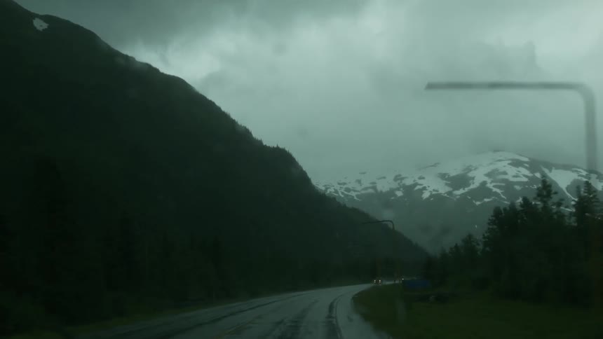 Vehicles travel down a wet mountain road