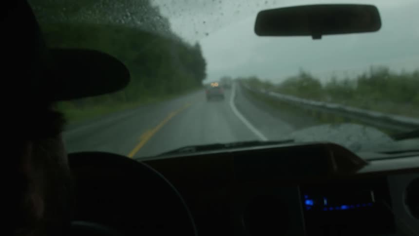 Person driving a car gestures and talks on a rainy day