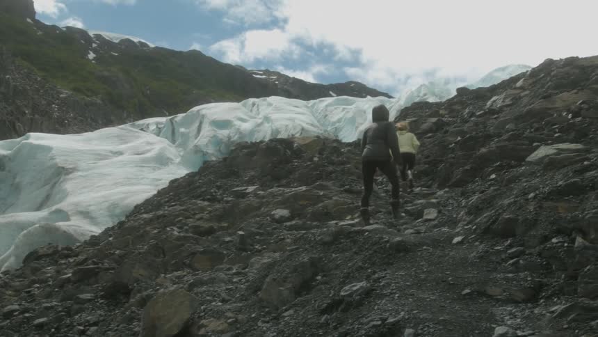 Two women hike up a snowy mountainside
