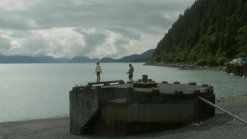 Man and woman stand on building next to lake