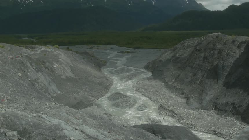 A ice covered cliffside overlooks a green valley below