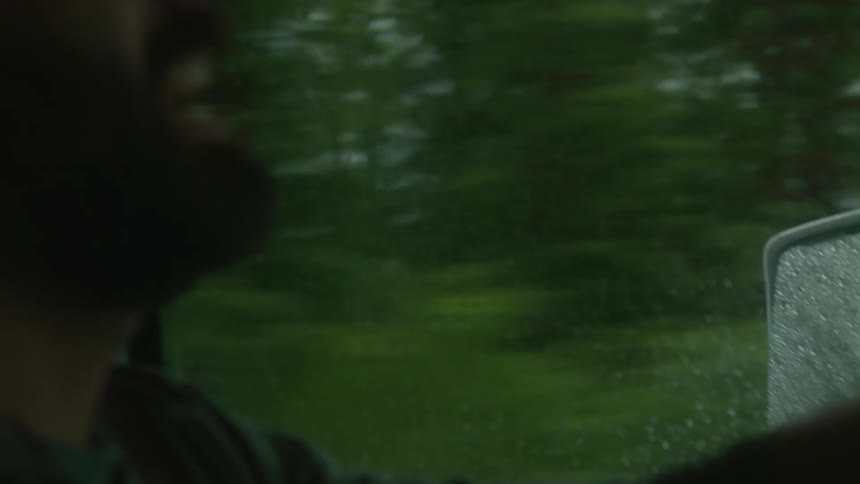 A driver is shouting and looking out the windows as he drives