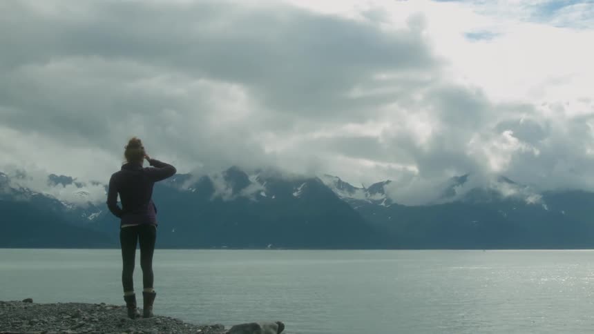 Woman walks next to mountain lake