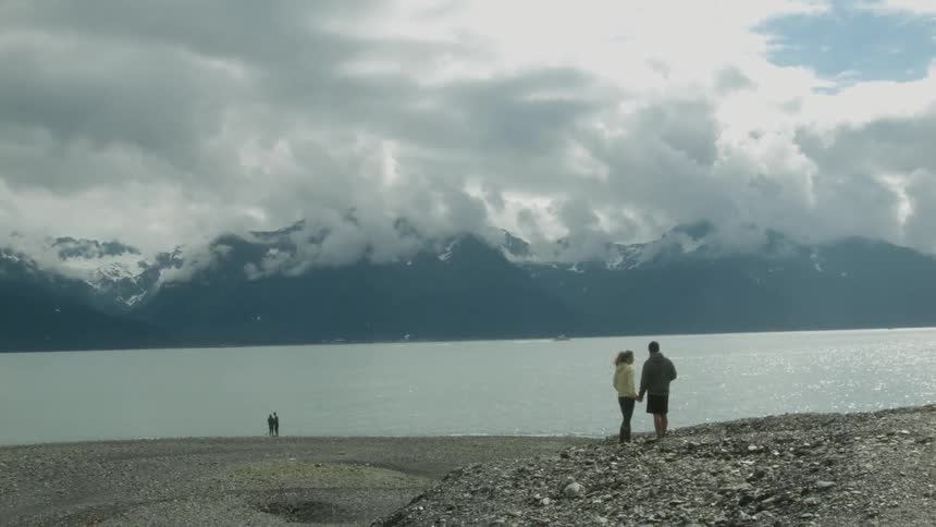Two people hold hands and walk towards the lake