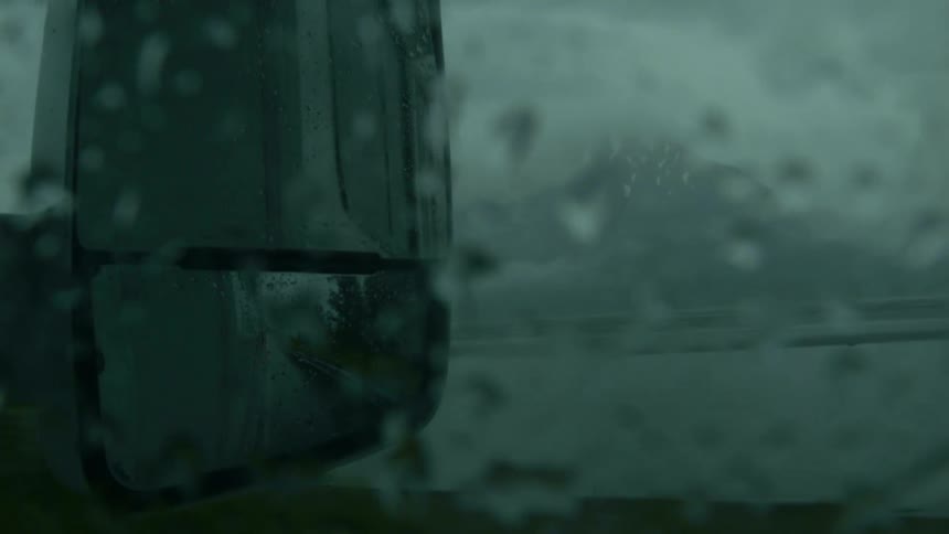 Vehicle drives next to a lake during a rainstorm