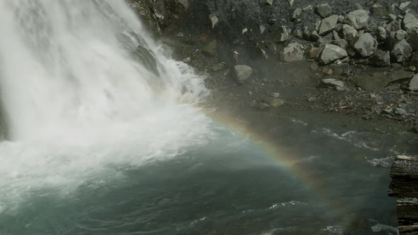 A large waterfall is creating mist which is turning into a rainbow