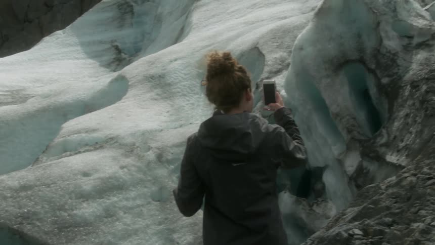 Woman brushes hair with hand and takes a picture of nature