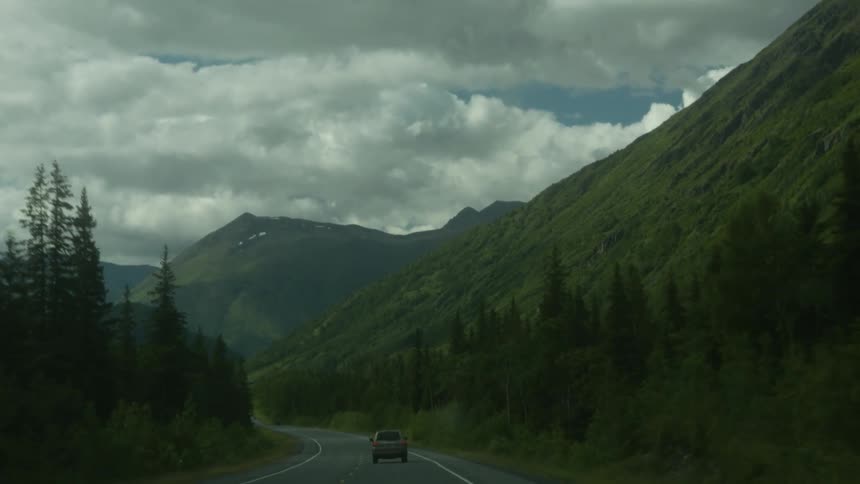Car drives down a road through the mountains