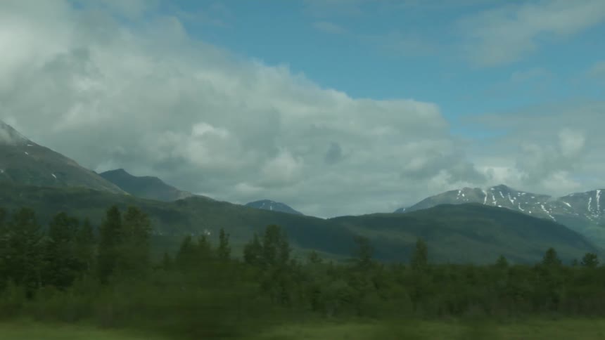 Trees line the field before the mountains ahead