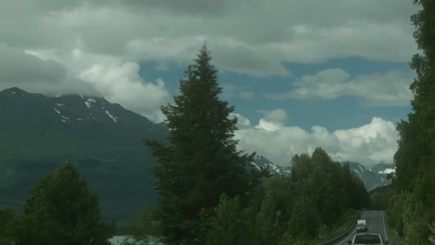 Cars travel down the small road by the mountain