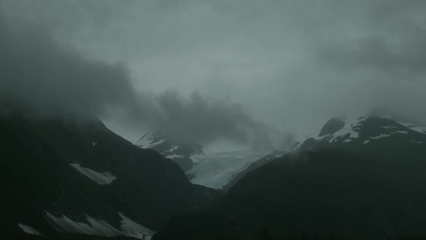 Clouds hover over snowy mountains