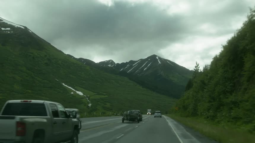 The cars are traveling down the road on a cloudy day