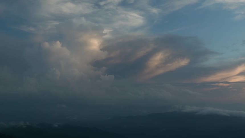 Clouds float over mountains at sunset