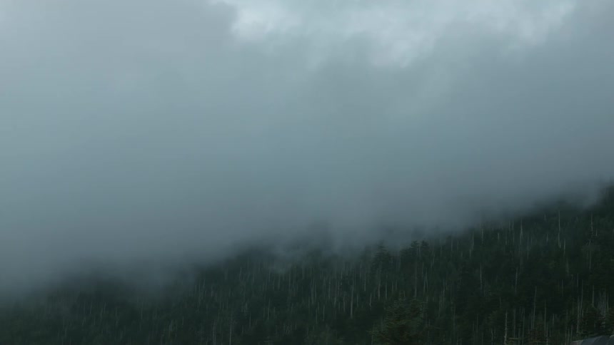 A foggy valley is filmed from a hill