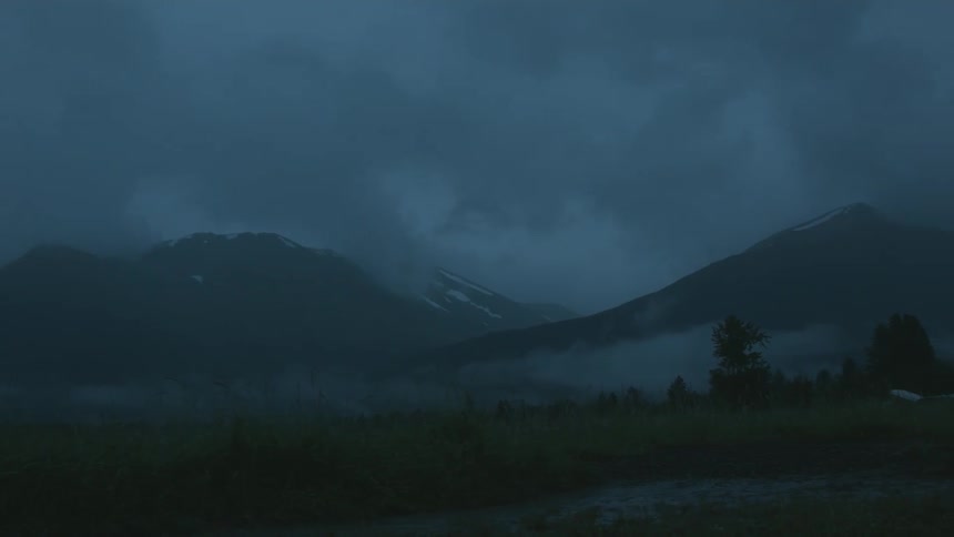 Fog and clouds hang over a mountain landscape at dusk