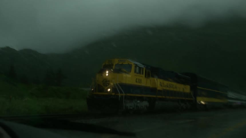 A train races by a moving vehicle at dawn