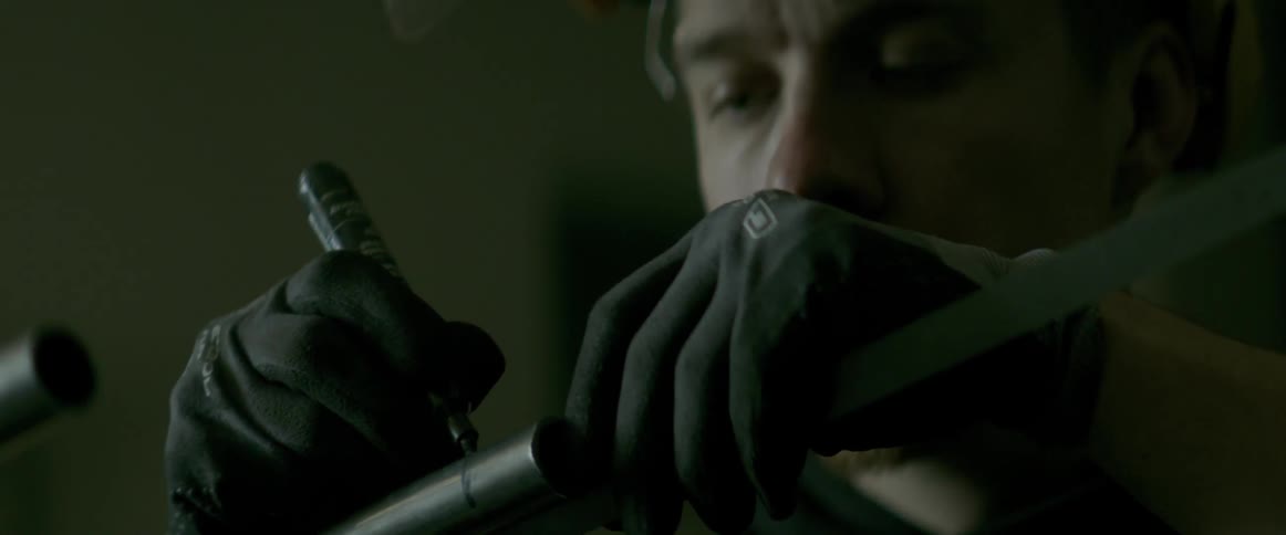 A man is marking a line on a piece of lead pipe