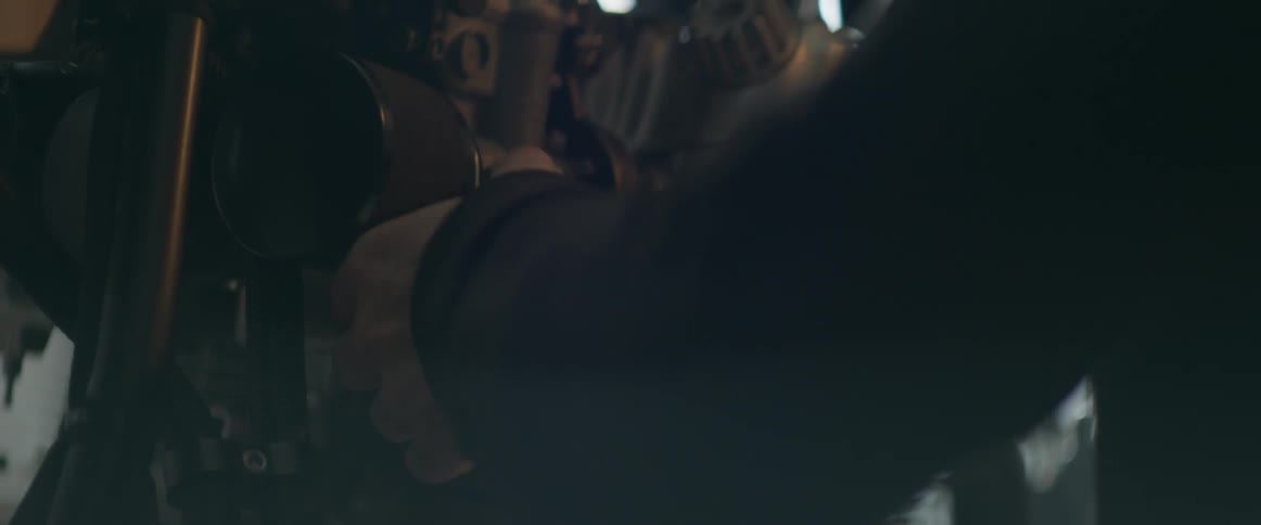 A man is using a socket wrench to unbolt an engine part