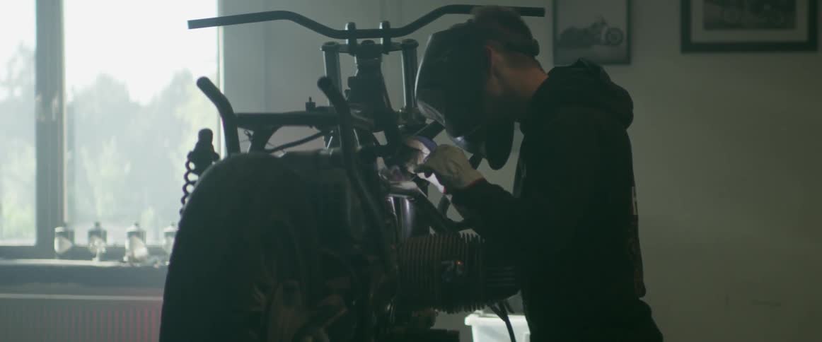 A man welds a bike while wearing a mask