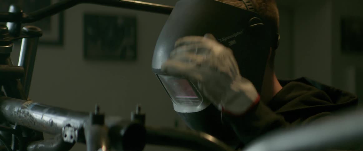A man flips his welding mask down as he begins to work