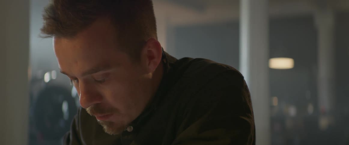 A man is sitting at a desk and looking down