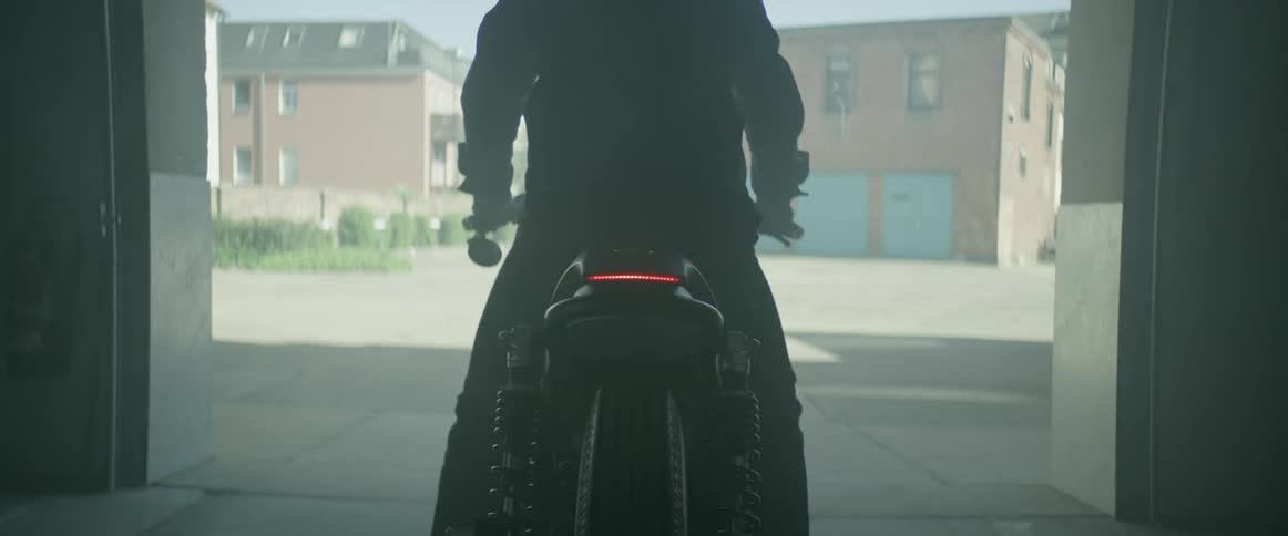 A man rides his bike out of a garage and into the street on a sunny day
