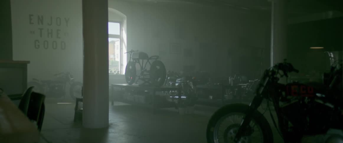 Motorcycles sit on tables in a workshop