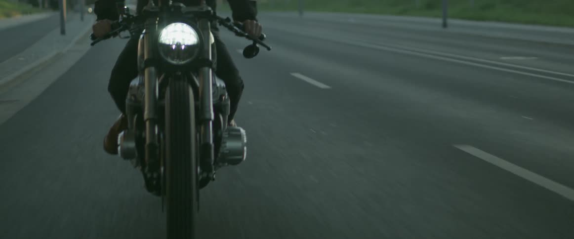 A man is riding a motorcycle at dusk