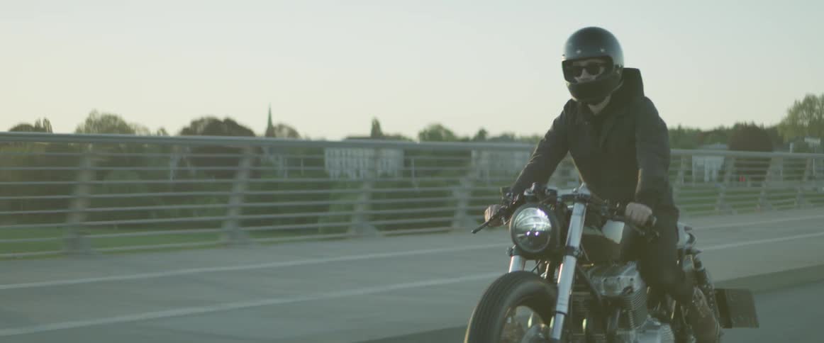 A man rides a motorcycle across a bridge